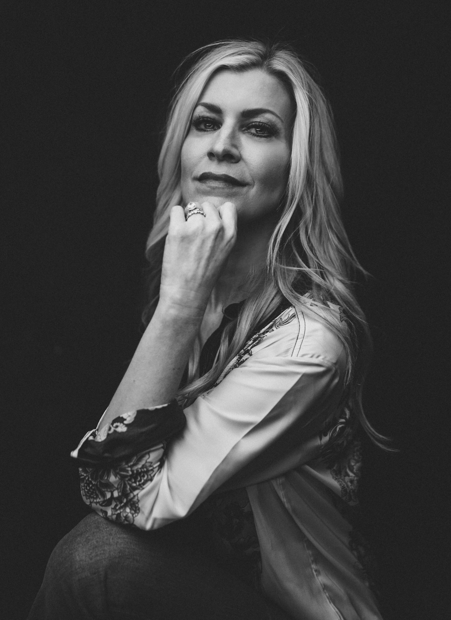 Black and white portrait of Jacy Ángelle Smith seated, her chin resting on her hand